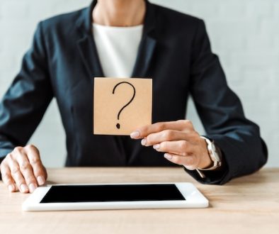 cropped view of woman holding sticky note with question mark near digital tablet