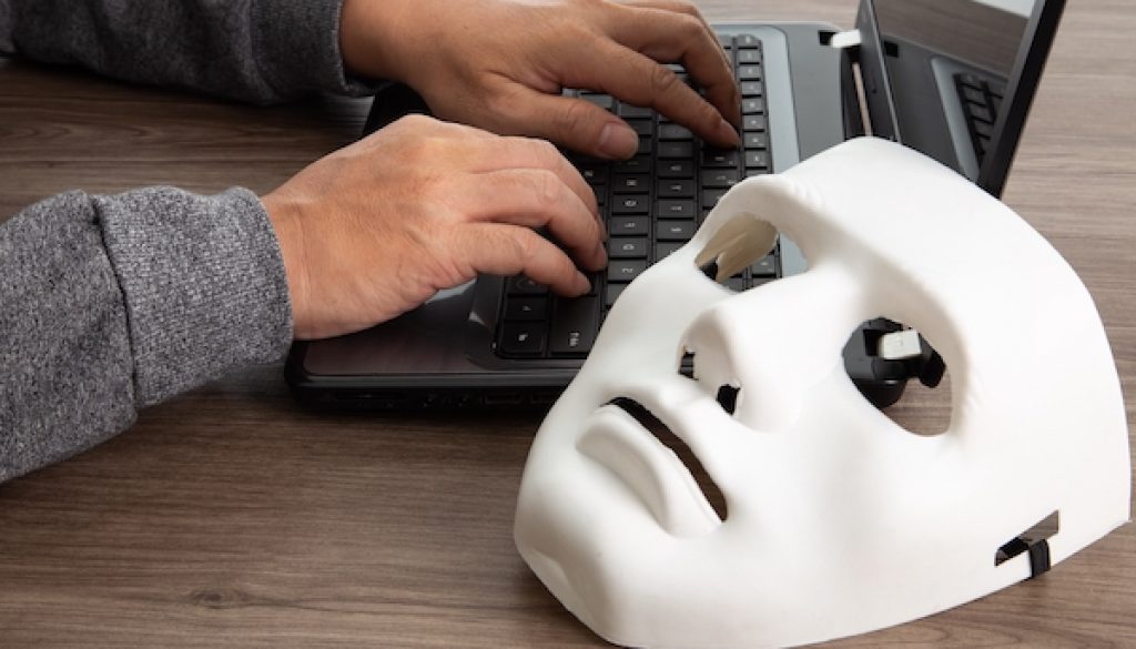 Thief hacker in mask stealing personal information from laptop