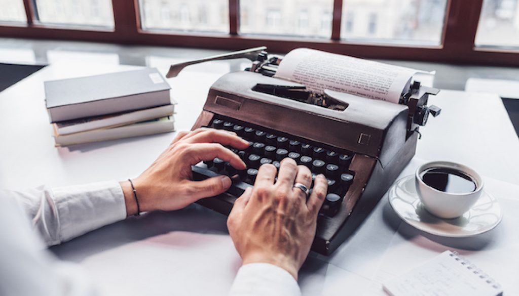 Young writer typing on a retro typewriter