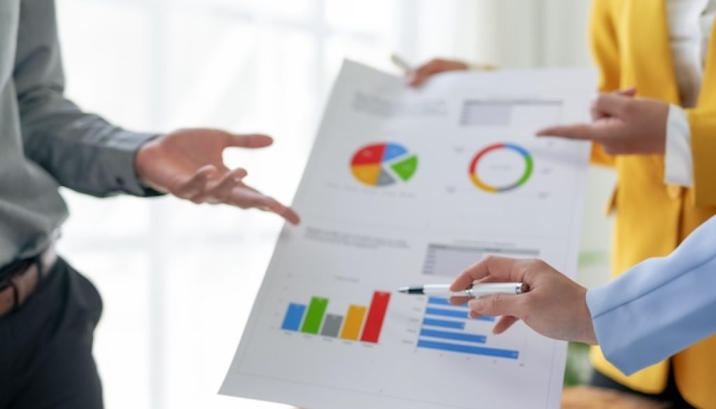 Business meeting with professionals discussing financial data and analysis reports in a modern office setting.