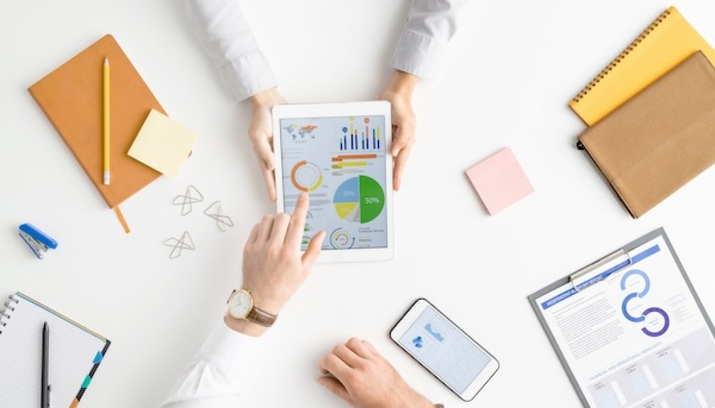 View of hands of two contemporary analysts or brokers discussing financial data