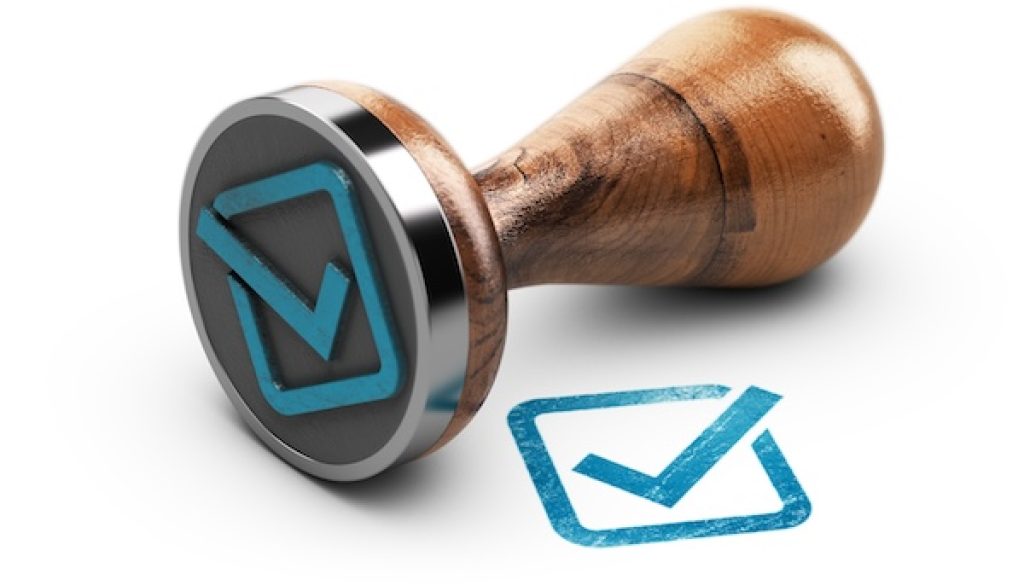 Check mark and rubber stamp over white background.
