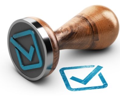 Check mark and rubber stamp over white background.